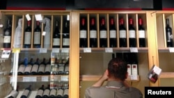 FILE - Bottles of Penfolds Grange, made by Australian wine maker Penfolds and owned by Australia's Treasury Wine Estates, are displayed as a shop assistant places more wine bottles onto shelves below at a wine shop in central Sydney, Australia, Aug. 2014