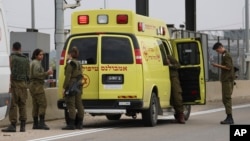 FILE - Israeli soldiers stand next to a military ambulance on a road near the West Bank Jewish settlement of Elkana, Nov. 15, 2022. A Palestinian killed two Israelis and wounded four others in an attack in a settlement before he was shot and killed by Israeli security personnel.