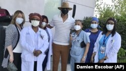 This image released by Damien Escobar shows Escobar with medical staff at Queens Hospital in the Queens borough of New York.