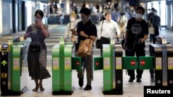 Passengers wearing protective face masks pass through the automated entranceway at a station amid the coronavirus disease (COVID-19) outbreak in Tokyo, Japan, July 23, 2020. 