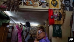 FILE - A woman waits to be shown a dress in a private clothing store in Havana, Cuba, Sept. 16, 2021. The United States said on May 28, 2024, that regulatory changes will allow Cuba’s independent private sector entrepreneurs to open and remotely access U.S. bank accounts.