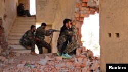Kurdish People's Protection Units (YPG) fighters take up positions inside a damaged building in al-Vilat al-Homor neighborhood in Hasaka city, as they monitor the movements of Islamic State fighters, July 22, 2015.