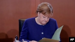 German Chancellor Angela Merkel reads documents after she arrives for the weekly cabinet meeting of the German government at the chancellery in Berlin, Germany, Jan. 8, 2020.