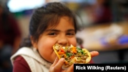 FILE - Maria Sandoval, a student in the Munroe Elementary School gardening club enjoys a meal she helped prepare by growing and chopping vegetables at the school in Denver, Colorado May 9, 2012. (REUTERS/Rick Wilking)