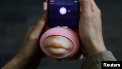 Jing Zhiyuan uses a remote kissing device "Long Lost Touch", as he demonstrates how to use it during an interview with Reuters, at his home in Beijing