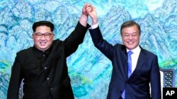 North Korean leader Kim Jong Un, left, and South Korean President Moon Jae-in raise their hands after signing a joint statement at the border village of Panmunjom in the Demilitarized Zone, South Korea, April 27, 2018.