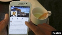 រូបឯកសារ៖ អ្នក​ប្រើប្រាស់​ទូរស័ព្ទ​ទំនើប smartphone មួយ​ចុច​មើល​ទំព័រ​ហ្វេសប៊ុក​របស់​លោក​នាយរដ្ឋមន្ត្រី ហ៊ុន សែន នៃ​ប្រទេស​កម្ពុជា​ក្នុង​ពេល​ទទួល​អាន​អាហារ​ពេល​ព្រឹក​នៅ​ក្នុង​ភោជនីយដ្ឋាន​មួយ​នៅ​កណ្តាល​រាជធានី​ភ្នំពេញ​កាល​ពី​ថ្ងៃ​ទី​៧ ខែ​តុលា ឆ្នាំ​២០១៥។