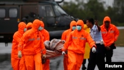 Search and Rescue crews carry part of AirAsia QZ8501 transported to shore by a Singapore Navy helicopter at the airbase in Pangkalan Bun, Central Kalimantan, Jan. 4, 2015. 