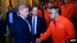 Perdana Menteri Pakistan Shehbaz Sharif (kedua dari kiri) menjabat tangan salah satu pekerja asal China dalam kunjungannya ke Dasu, Pakistan, tempat pembangunan Pembangkit Listrik Tenaga Air pada 1 April 2024. (Foto: AFP/Pakistan's Press Information Department)