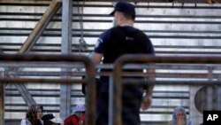 FILE - Migrants wait to board buses during a police operation to evacuate an unused terminal building of the old international airport, in Athens, June 2, 2017. 