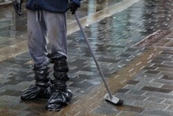 A man cleans mud from the street in Pontypridd in south Wales, Feb. 16, 2020.