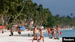 Tourists walk on White Beach on the resort island of Boracay, south of Manila, Feb. 2, 2008. 