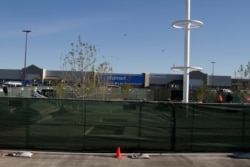 Construction workers stand near a memorial they are building for the 22 people killed at the Cielo Vista Walmart seen in the background, Nov. 14, 2019, in El Paso, Texas, minutes before the store was reopened.