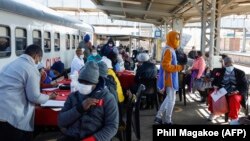 Des patients s'inscrivent à l'extérieur de la clinique mobile du train Transnet-Phelophepa pour recevoir des soins de santé à la gare de Dube à Soweto, le 22 juin 2021.