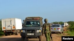 FILE - A Kenyan police officer observes motor vehicle traffic near the scene where armed assailants killed three people and injured two others in Nyongoro area of Lamu County, Kenya, Jan. 2, 2020.