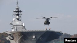 FILE - A helicopter lands on the Izumo, Japan Maritime Self Defense Force's (JMSDF) helicopter carrier, at JMSDF Yokosuka base in Yokosuka, south of Tokyo, Japan, Dec. 6, 2016. 