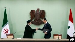 Presiden Suriah Bashar Assad (kanan) berjabat tangan dengan Presiden Iran Ebrahim Raisi setelah mereka menandatangani perjanjian kerja sama di Damaskus, Suriah, pada 3 Mei 2023. (Foto: AP/Omar Sanadiki)