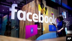 In this Tuesday, April 18, 2017, file photo, a conference worker passes a demo booth at Facebook's annual F8 developer conference in San Jose, Calif. (AP Photo/Noah Berger, File)