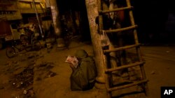 FILE - A homeless Indian reads the newspaper before sunrise in the old city area of New Delhi, India, Wednesday, Feb. 11, 2015. Some 800 million people in the country live in poverty, many of them migrating to big cities in search of a livelihood.