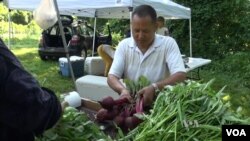 Refugee farmer Dhan Subba sells the vegetables that he grows. (VOA)
