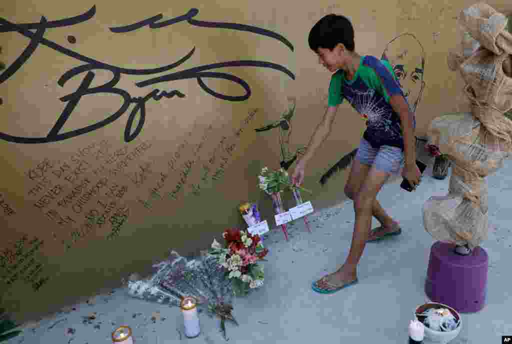 A boy places flowers on a wall with an image and signature of former NBA basketball player Kobe Bryant at the &#39;House of Kobe&#39; basketball court in Valenzuela, north of Manila, Philippines on Jan. 27, 2020. 