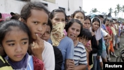Typhoon evacuees queue for relief goods outside a local government town center in New Bataan, Compostela Valley in southern Philippines, December 6, 2012. 