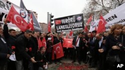 Turkish civil servants hold a banner that reads "We condemn terrorism" as they lay carnations at the site of Wednesday's explosion that killed 28 people in Ankara, Feb. 20, 2016.