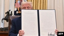 Presiden AS Donald Trump menunjukkan lembar Instruksi Presiden yang ia tandatangani terkait deklasifikasi dokumen kasus pembunuhan sejumlah tokoh penting seperti mantan Presiden John F. Kennedy, di Gedung Putih, Washington, DC, pada 23 Januari 2025. (Foto: AFP/Roberto Schmidt)