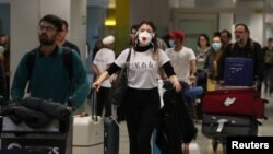 Un voyageur, portant un masque pour éviter le coronavirus, arrive à l'aéroport international de Guarulhos à Guarulhos, État de Sao Paulo, Brésil, le 27 février 2020. (Photo: REUTERS / Amanda Perobelli)