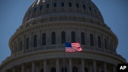 FILE - An American flag is seen flying in front of the dome of the United States Capitol building, July 26, 2011.