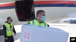 FILE - In this photo provided by the Serbian Presidential Press Service, a worker holds a box of the AstraZeneca vaccines at Sarajevo Airport, Bosnia, March 2. 2021.