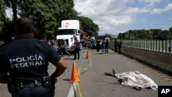 A Central American migrant, who fell from the back of a moving vehicle and died, lies on a highway covered by a sheet outside of Tapachula, Mexico, Oct. 22, 2018.