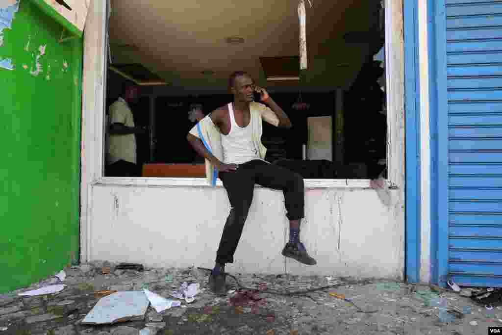 A man sits outside looted Tumaini supermarket in Kisumu, Kenya, during anti-electoral commission protests on October 6, 2017, ahead of the upcoming re-run presidential election. (VOA/J. Craig)