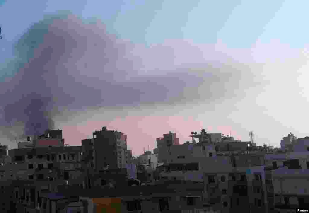 Smoke rises behind building from the site of an explosion in Beirut's southern suburbs, August 15, 2013. 