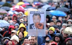 FILE - Employers of Hungary's opposition radio, the Klubradio, and their sympathizers hold umbrellas with a photo of Hungarian Prime Minister Victor Orban in Budapest, Feb. 24, 2013.