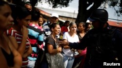 Des proches de détenus discutent avec un policier en attendant des informations après une émeute et un incendie dans les cellules du quartier général de la police de Carabobo à Valence, au Venezuela, le 29 mars 2018.