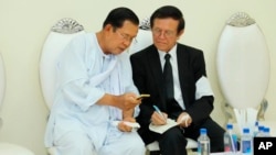 លោកនាយករដ្ឋមន្ត្រី ហ៊ុន សែន (ឆ្វេង) និយាយជាមួយនឹងលោក កឹម សុខា មេដឹកនាំគណបក្សសង្គ្រោះជាតិដែលត្រូវបានតុលាការកំពូលរំលាយ ក្នុងពិធីបុណ្យសពម្ដាយក្មេករបស់ លោក ហ៊ុន សែន ក្នុងរាជធានីភ្នំពេញ ថ្ងៃទី៥ ខែឧសភា ឆ្នាំ២០២០។ (Pool via AP)