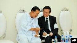 Cambodian Prime Minister Hun Sen, left, talks with dissolved main opposition Cambodia National Rescue Party leader Kem Sokha at the mourning ceremony of Sen's mother in-law, in Phnom Penh, Cambodia, Tuesday, May 5, 2020. (Pool via AP) 