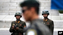 In this April 17, 2017, file photo, two North Korean soldiers look at the south side as a South Korean soldier, center, standing guard at the border village of Panmunjom which has separated the two Koreas since the Korean War, South Korea.