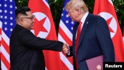 Presiden AS, Donald Trump, dan pemimpin Korea, Kim Jong Un, berjabat tangan dalam acara penandatanganan dokumen setelah pertemuan puncak antara kedua pemimpin di Capella Hotel, Pulau Sentosa, Singapura, 12 Juni 2018 (foto: Susan Walsh/Pool via Reuters)