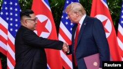 រូបឯកសារ៖ លោក​ប្រធានាធិបតី​អាមេរិក ដូណាល់ ត្រាំ និង​មេដឹកនាំ​កូរ៉េ​ខាង​ជើង​ លោក គីម ជុនអ៊ុន ចាប់​ដៃគ្នាបន្ទាប់ពី​បាន​ចុះ​ហត្ថលេខា​លើ​កិច្ចព្រមព្រៀង​មួយ​នៅ​សណ្ឋាគារ Capella ប្រទេស​សិង្ហបុរី កាលពី​ថ្ងៃទី១២ ខែមិថុនា ឆ្នាំ២០១៨។​ (រូបថត Reuters)