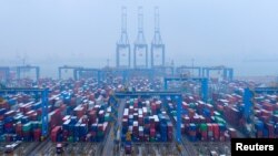 FILE - Containers and trucks are seen on a snowy day at an automated container terminal in Qingdao port, Shandong province, China, Dec. 10, 2018, 