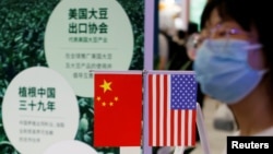 រូបឯកសារ៖ ស្ត្រី​ម្នាក់​ដើរ​កាត់​ទង់ជាតិ​ចិន​និង​សហរដ្ឋ​អាមេរិក​នៅ​កន្លែង​តាំង​ពិព័រណ៍​ទំនិញ​អន្តជាតិ​ ក្នុង​ទីក្រុង​ប៉េកាំង​ ប្រទេស​ចិន ថ្ងៃទី៤ ខែកញ្ញា ឆ្នាំ២០២២។ (REUTERS)