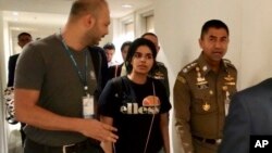 In this photo released by the Immigration Police, Chief of Immigration Police Maj. Gen. Surachate Hakparn, right, walks with Saudi woman Rahaf Mohammed Alqunun before leaving the Suvarnabhumi Airport in Bangkok, Thailand, Jan. 7, 2019.