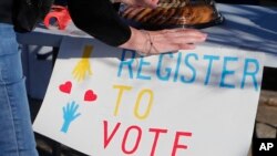 FILE - A voting drive volunteer sets up a table in Richardson, Texas, Jan. 18, 2020. Democrats are anxious about the coming presidential election and Republicans are more likely to be excited about it. 