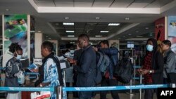 FILE - Passengers are asked to desinfect their hands upon arrival from international flights before being screened to detect signs of the coronavirus, at Entebbe Airport, in Entebbe, Uganda, March 3, 2020.