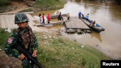 FILE - A soldier stands guard on the Thai side of the river as people prepare to cross into Malaysia in Sungai Kolok in southern Narathiwat province, March 8, 2013. 