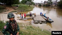 FILE - A soldier stands guard on the Thai side of the river as people prepare to cross into Malaysia in Sungai Kolok in southern Narathiwat province, March 8, 2013. 