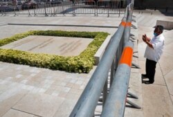 FILE - A man prays at the grave of former Lebanese Prime Minister Rafik Hariri, in downtown Beirut, Lebanon, Aug. 4, 2020.
