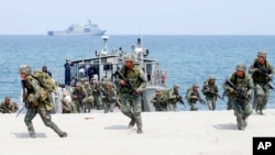 FILE - Philippine and U.S. Marines storm a beach as part of an amphibious landing exercise, May 9, 2018, during a two-week joint U.S.-Philippines exercise facing the South China Sea in the Philippines. 